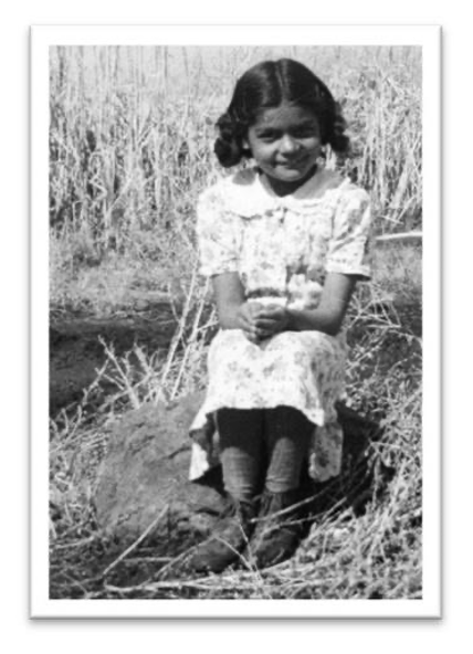 Carmelita as a young girl, sitting on a rock.
