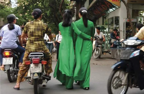 Women wearing green ao dais, traditional Vietnamese attire.
