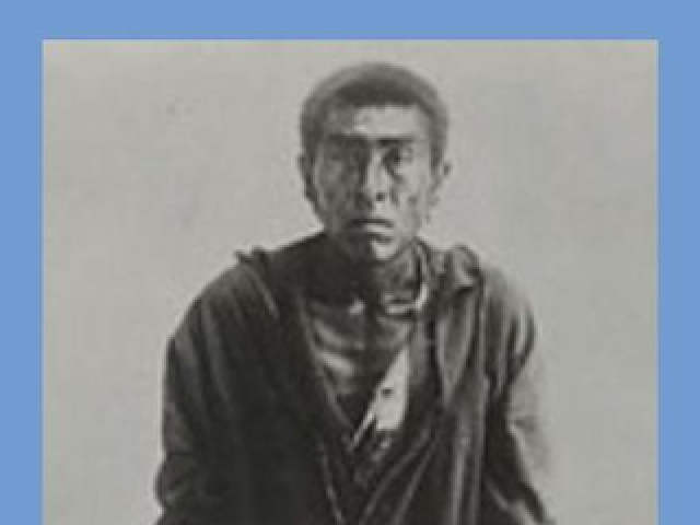 Ishi standing wearing a coat
