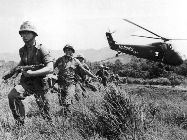 In this April 28, 1965 file photo, U.S. Marine infantry stream into a suspected Viet Cong village near Da Nang in Vietnam during the Vietnamese war. Filmmaker Ken Burns said he hopes his 10-part documentary about the War, which begins Sept. 17, 2017 on PBS, could serve as sort of a vaccine against some problems that took root during the conflict, such as a lack of civil discourse in America