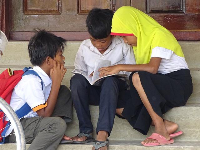 Young Cham students looking at a book.