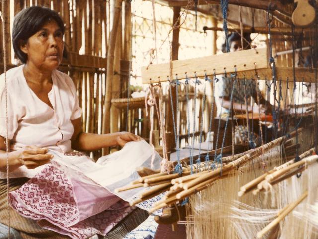 Silk production and weaving are an important part of Cambodian cultural heritage as well as a source income for many Cambodian families, especially in rural areas of Cambodia. Textiles are produced using various regional designs and traditional motifs for scarves (krama), traditional clothing, and decorative fabrics. In this photo, a Cambodian woman is working at a wooden weaving loom in Cambodia. (Photo courtesy of Bonnie Lowenthal)