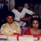 In this photo, the bride’s hair is symbolically cut in the Kat Sak (Hair cutting) wedding ceremony to represent a fresh start. Relatives and friends take turns cutting the hair of the bride and groom to cleanse the couple in preparation for their new life together and to bestow blessings of good fortune, happiness, prosperity, and longevity.