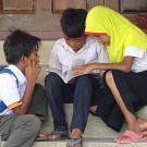 Young Cham students looking at a book.