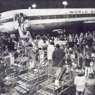4/2/1975 The East side of Hangar 110, Oakland International Airport as Members of the press and others meeting the first “un-official” flight of Vietnamese orphans. The bus seen in the picture was one of several that transported the arriving orphans to the Armory at the San Francisco Presidio.
