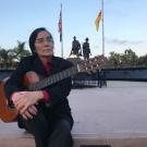Famous composer Trần Chí Phúc, known for his work on “refugee music,” stands next to the Vietnam War Memorial in Liberty Park, Westminster, CA.
